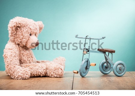 Retro Teddy Bear and old toy bicycle with three wheels front gradient mint green wall background. Vintage instagram style filtered photo