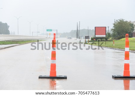 High water at frontage road North Sam Houston Parkway Northeast of Houston. Traffic cone block, pickup truck swamped by flood in distance. Harvey Tropical Storm disaster Motor Vehicle Insurance theme