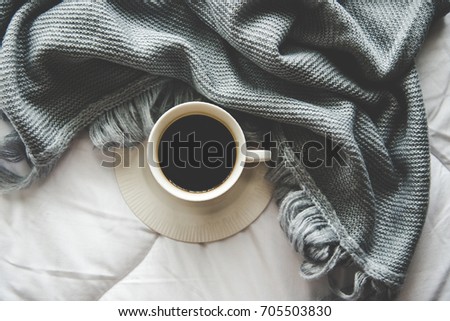 Coffee with Cozy winter interior home background, cup of hot tea marshmallow, warm knitted sweater on white bed background, vintage tone.  Lifestyle concept.