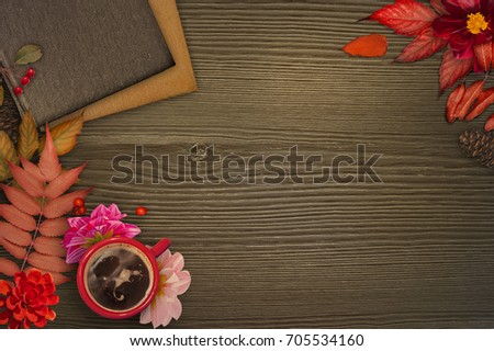 Autumnal background. Red cup of coffee, books with autumnal red leaves, pink georgina on dark wooden background. Workspace on brown wood background. Place for text