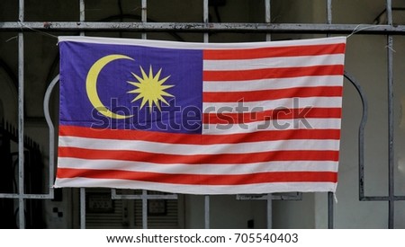A Malaysian Flags with a blue, white, red and yellow with a 14 stripes, moon and stars. It's a symbol of Unity, Sovereign and Respect.
