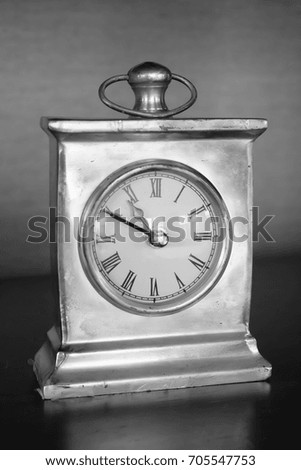Vintage and antique design table or desk time clock made from metal, black and white photo