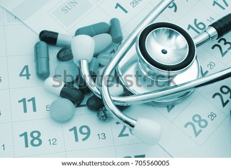 Stethoscope with drugs and pills on calendar pages