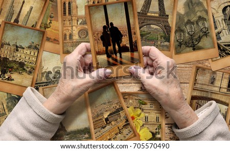 Old female hands hold old travel photo. Vintage photo cards on the wood background. Remembering Paris. European tourism and vacation travel. Memory and dreams concept. Royalty-Free Stock Photo #705570490