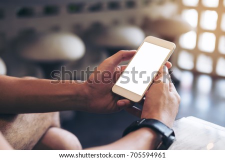 Mockup image of man's hands holding white mobile phone with blank screen in modern cafe