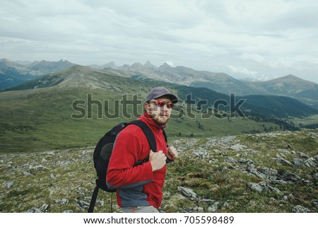 Man traveler with backpack hiking on mountains.Travel Lifestyle adventure active summer outdoor rocky mountains on background