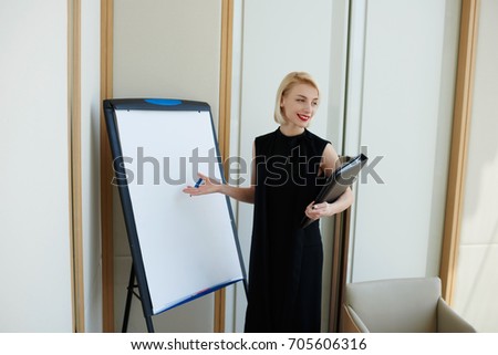 Positive female marketing expert dressed in formal outfit making speech on presentation satisfied with successful project; attractive businesswoman having conference meeting explaining working plan