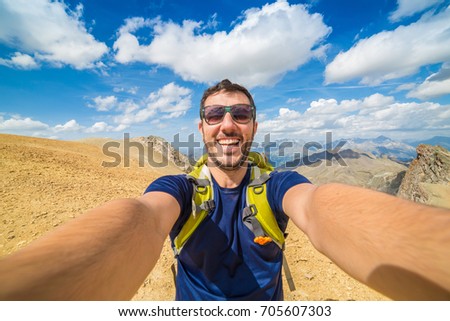 man hiker photographer taking selfie on the mountains background in the Alps