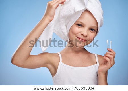 a girl in a white towel on her head holds eared sticks on a blue background                               