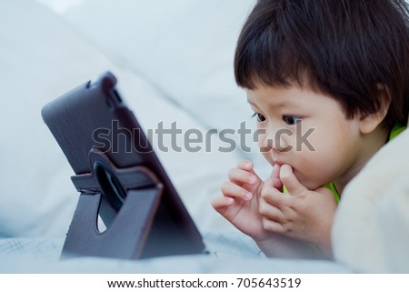 asian children watching tablet  / playing phone and looking at cartoon
