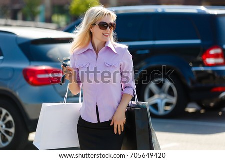beautiful girl with shopping bags near a her car