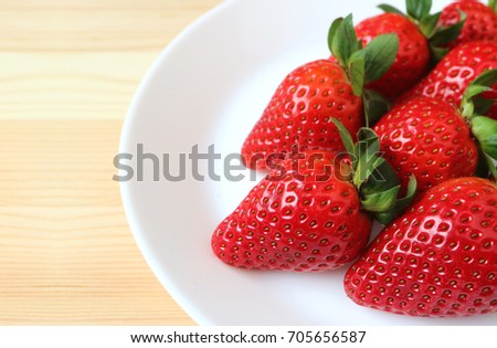Vibrant Red Fresh Ripe Strawberries Lined up on a White Plate on Wooden Table 