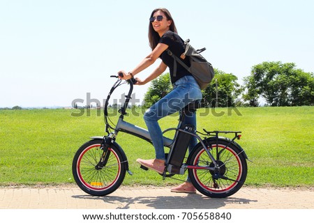 A smiling woman with electric bicycle  in the park