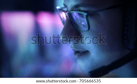 Close-up Shot of Professional Gamer Plays in MMORPG/ Strategy Video Game on His Computer. He's Participating in Online Cyber Games Tournament,  or in Internet Cafe. He Wears Glasses and Headsets. Royalty-Free Stock Photo #705666535