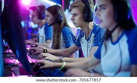 Team of Professional eSport Gamers Playing in Competitive Video Games on a Cyber Games Tournament. They using Microphones.