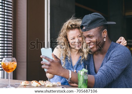 Loving couple watching the smart phone during aperitif in a local