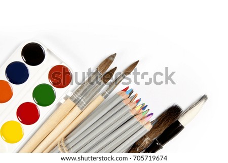 Set of colored pencils, paint brushes and watercolor paint-box isolated on the white