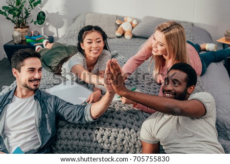 group of young happy students giving high five