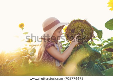 Little cute girl in sunflowers at sunset