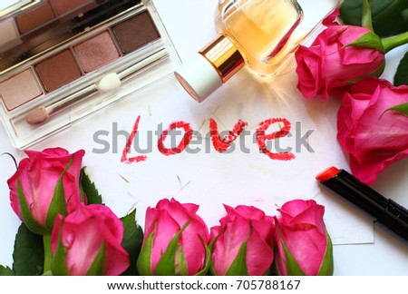 set of decirative cosmetics (eye shadows, parfume and lipstick) top view. Cosmetics, fresh red roses and lettering of the word love. Woman's or mothers day background