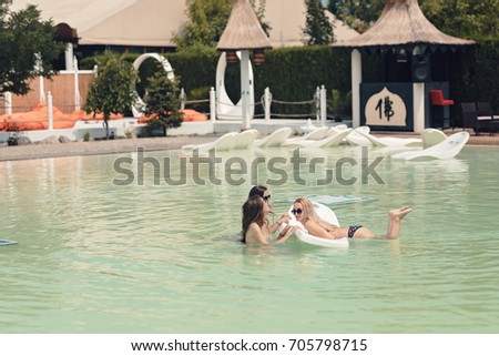 Cool young girls enjoy the beautiful summer pool and the excellent sun while tanning on the floating sunbed.Dream the perfect holiday in amazing seaside resort sunbathing and being happy in the nature