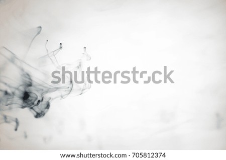 Black ink dissolving in water resembling smoke