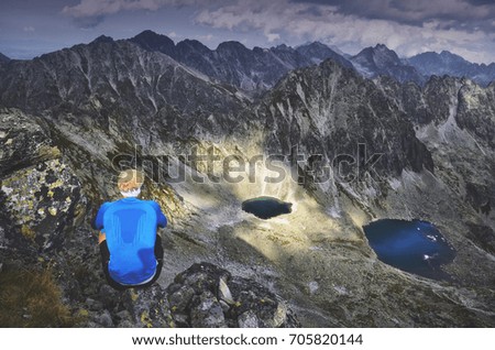 Tourist in blue and dark scenery in mountains - photo with edit space