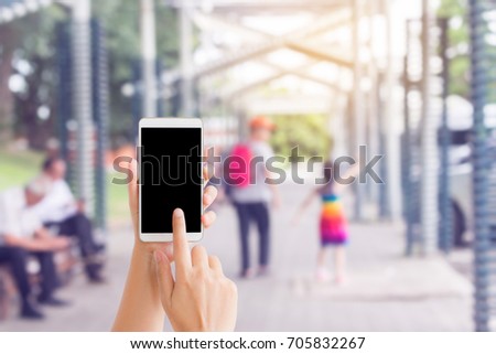 woman use mobile phone and blurred image of people on the walkway in the garden
