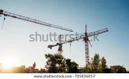 beautiful building site picture with industrial cranes on warm evening sunlight