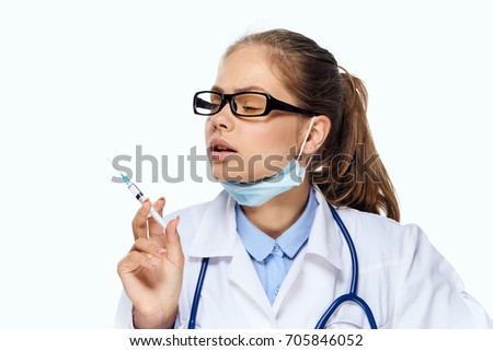 Doctor young in glasses with a syringe on a light background                               