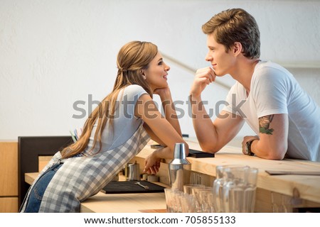 side view of handsome man and young woman flirting and smiling each other while working n cafe Royalty-Free Stock Photo #705855133