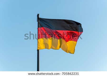 The German flag on a pole with blue sky isolated
