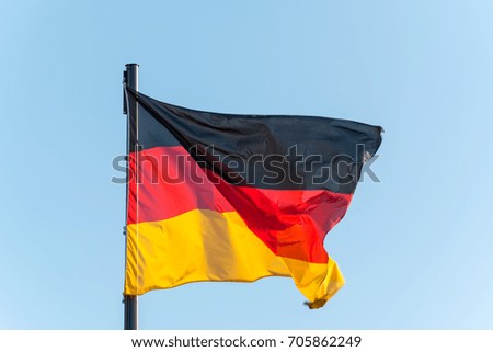 The German flag on a pole with blue sky isolated