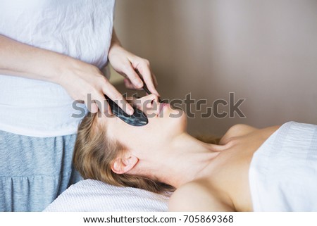 Young woman have face guasha treatment at asian beauty clinic