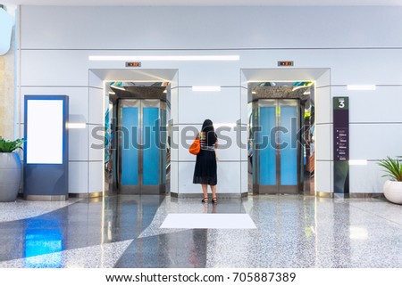 Woman standing between the elevators while waiting for elevator going up.