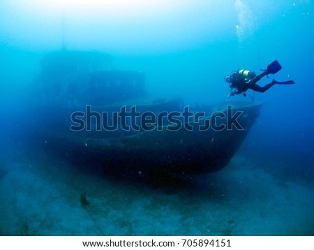 scuba diver exploring ship wreck underwater