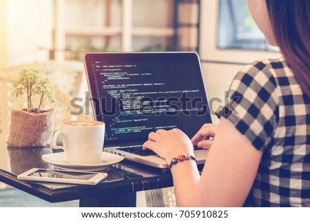 A female programmer typing source codes in a coffee shop with a relaxing working environment. Studying, Working, Technology, Freelance Work, Web Design Business, and Web Development Concept. Royalty-Free Stock Photo #705910825