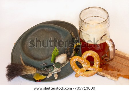 Green Felt German Hat with Feathers and Pins with Beer Stein and Pretzel on White Background