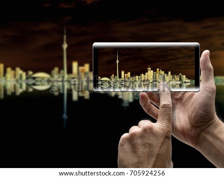 Two hands holding a mobile Smartphone and take a picture of Beautiful Toronto Cityscape with Water Reflection