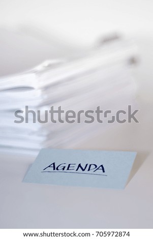 Agenda; Stack of Documents on white desk and Background.