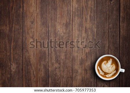 A cup of hot latte art or cappuccino coffee on wooden table. Top view