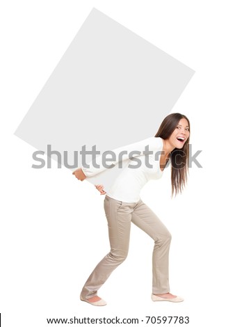 Woman lifting / showing heavy blank billboard sign. Woman carrying empty sign board on her back. Funny image of beautiful asian \ caucasian female model isolated in full length on white background. Royalty-Free Stock Photo #70597783