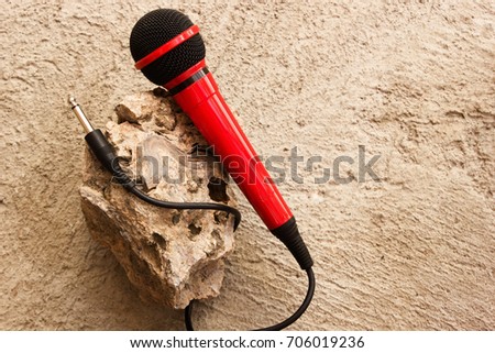 Stylish photo of a red wired microphone on a rocky background