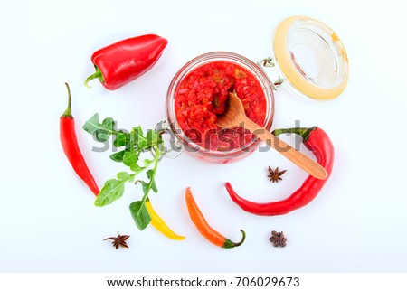 Sauce of red hot peppers in a glass jar, top view (on white background)