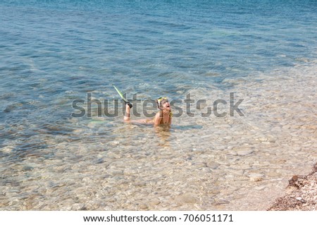 Beautiful girl in accessories for diving lies  in clear sea water