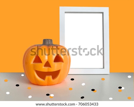 Happy Halloween orange background. Pumpkin toy smiling face. Plastic Jack o lantern light. Confetti Vertical white photo frame mock up template on table. Empty space. Trick or treat. Holiday symbol.