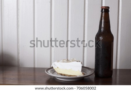 Fresh slice of lemon meringue pie and an unopened bottle of beer