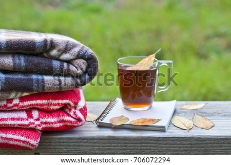 Tea in a glass cup and notepad for notes, the concept of autumn, yellow leaves and woolen blankets.