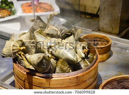 stack of traditional steamed chinese dumplings or zongzi in bamboo basket, sticky rice wrapped in bamboo leave for dumpling festival or dragon boat festival (selective focus)