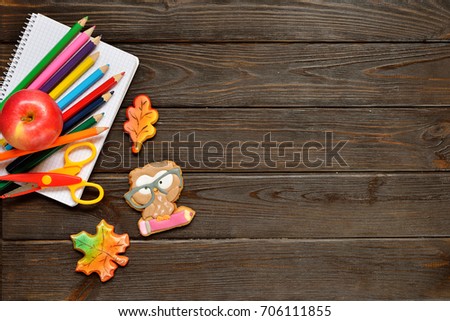 Back to school concept background with colored pencils, red appple and gingerbread on wooden table, flat lay